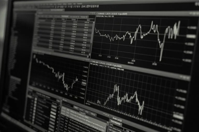 Monitor wyświetlający wykresy notowań giełdowych EUR/USD i złota z tabelą danych