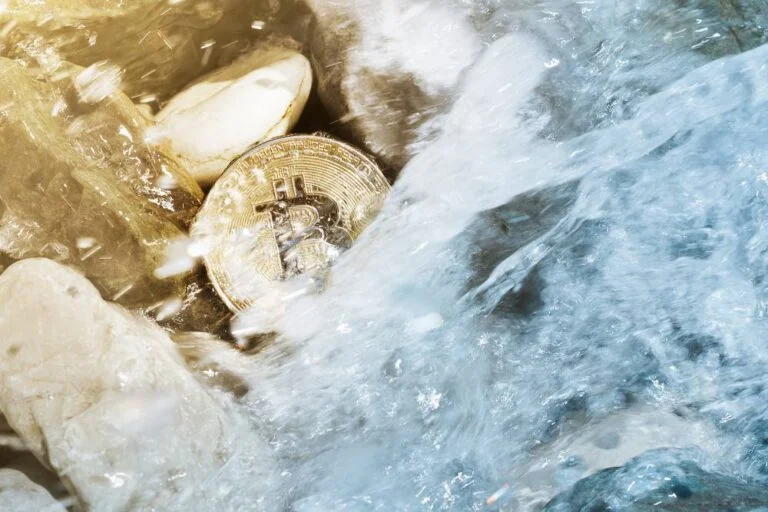 Moneta Bitcoin w strumieniu wody między kamieniami