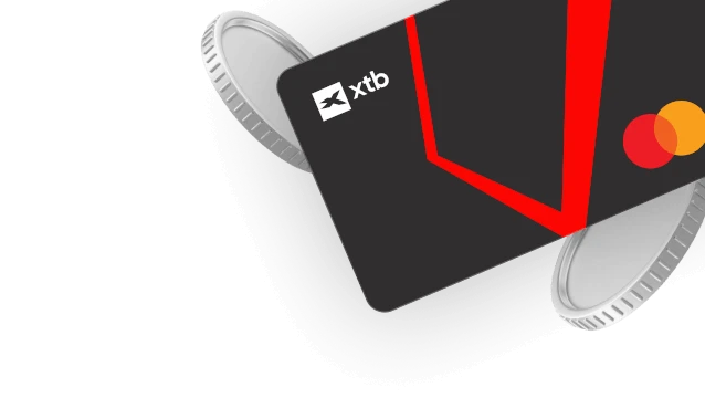 Czarna karta płatnicza XTB Mastercard otoczona srebrnymi monetami