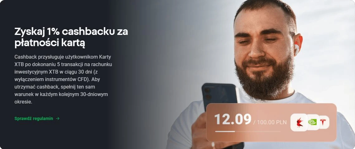 Mężczyzna z brodą trzymający smartfon, reklama cashbacku karty XTB